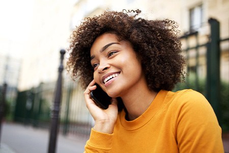 Woman smiling while talking on phone outside