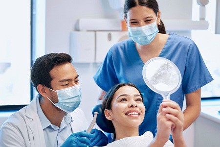 Patient looking at reflection in mirror with dentist