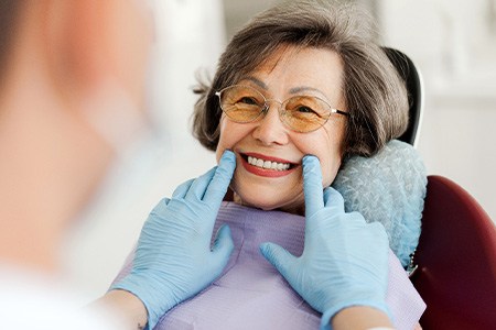 Dentist looking at smiling patient's dentures