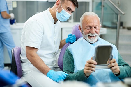 Senior patient smiling at reflection in handheld mirror