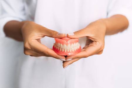 Lady presents viewer with dentures