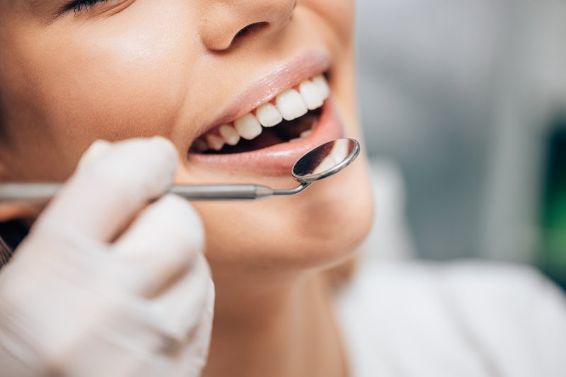 Woman smiles while receiving dental examination.